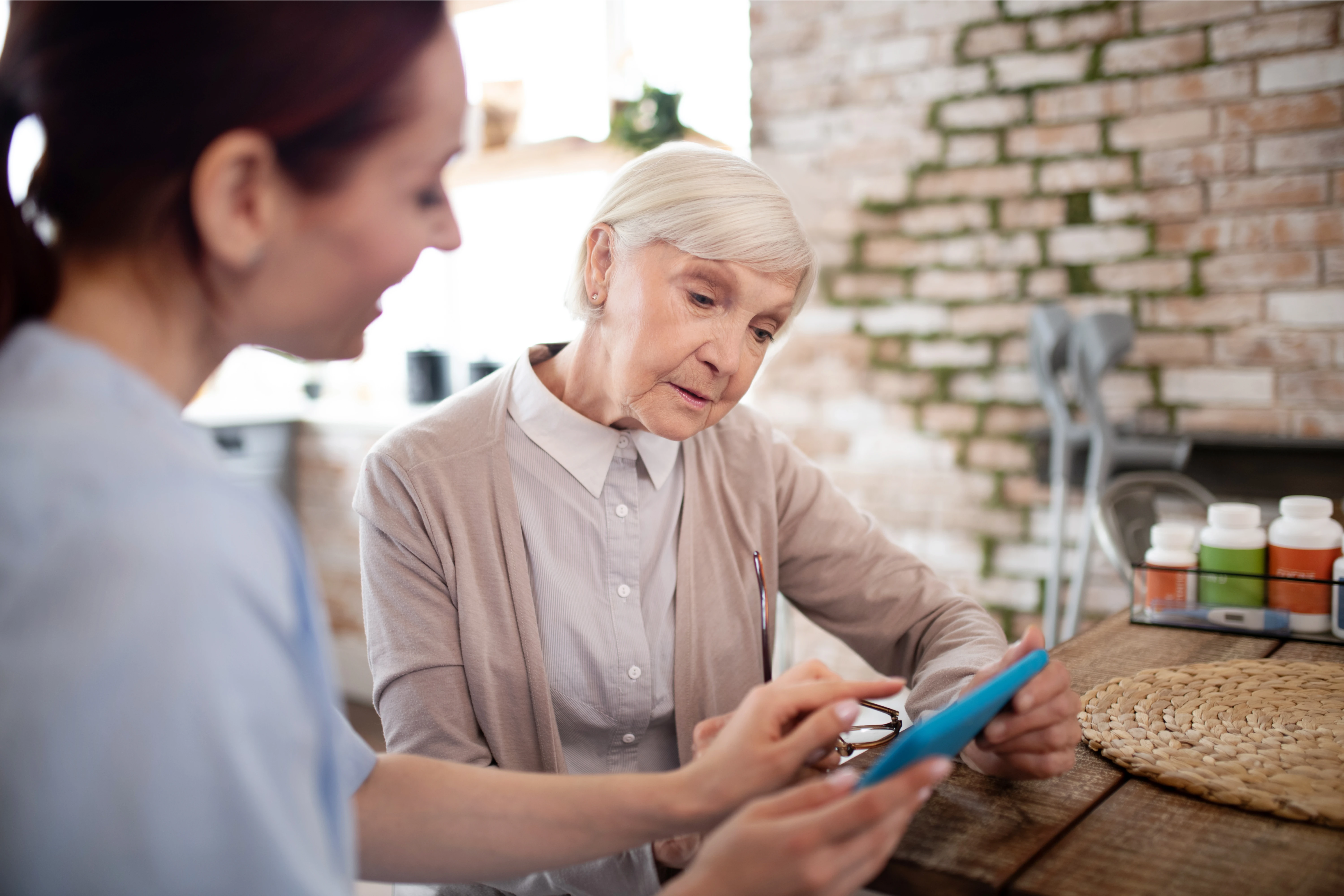 aged_woman_feeling_involved_using_tablet_with_caregiver_1