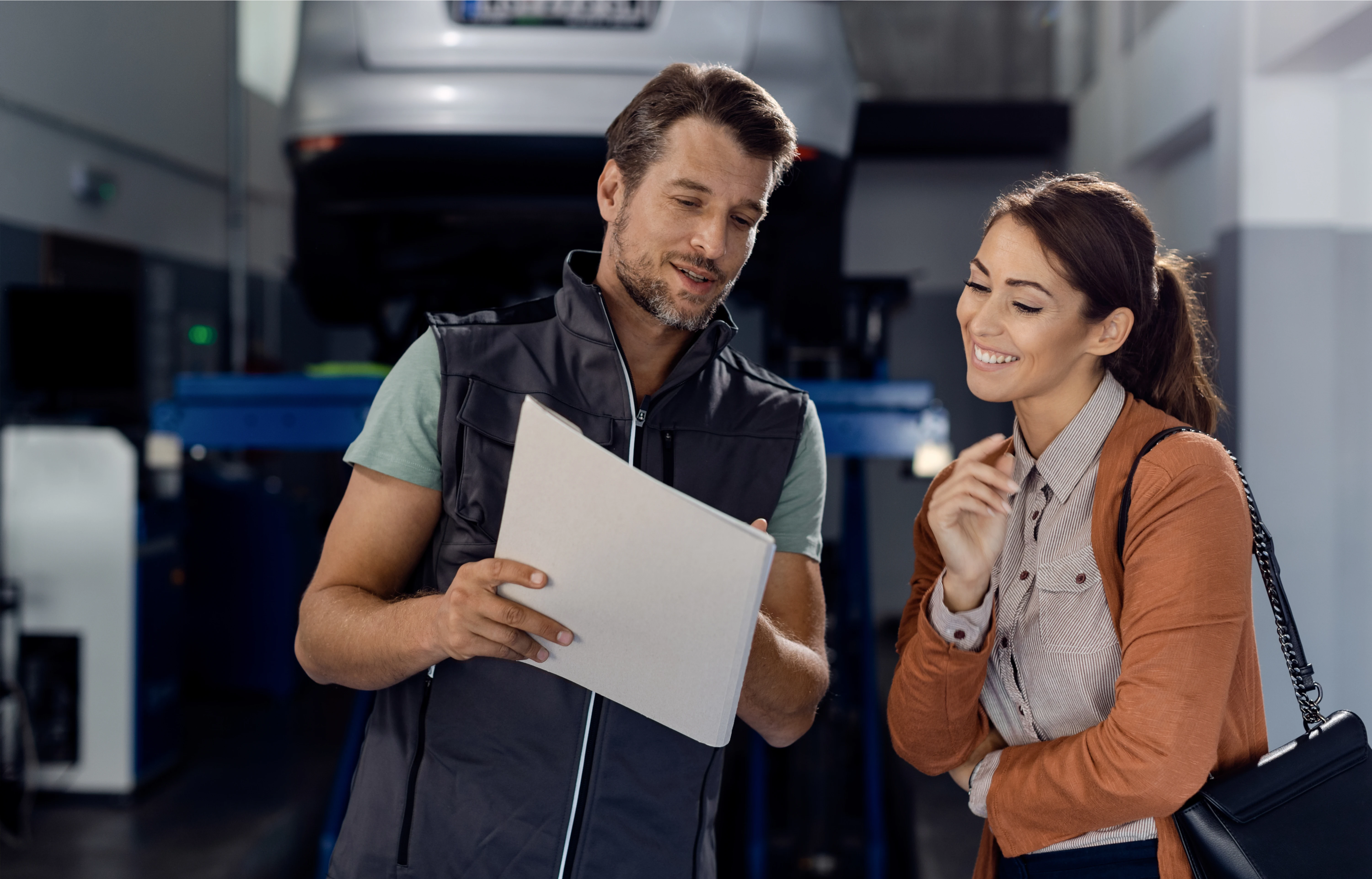 happy_mechanic_female_customer_going_through_paperwork_auto_repair_shop_1