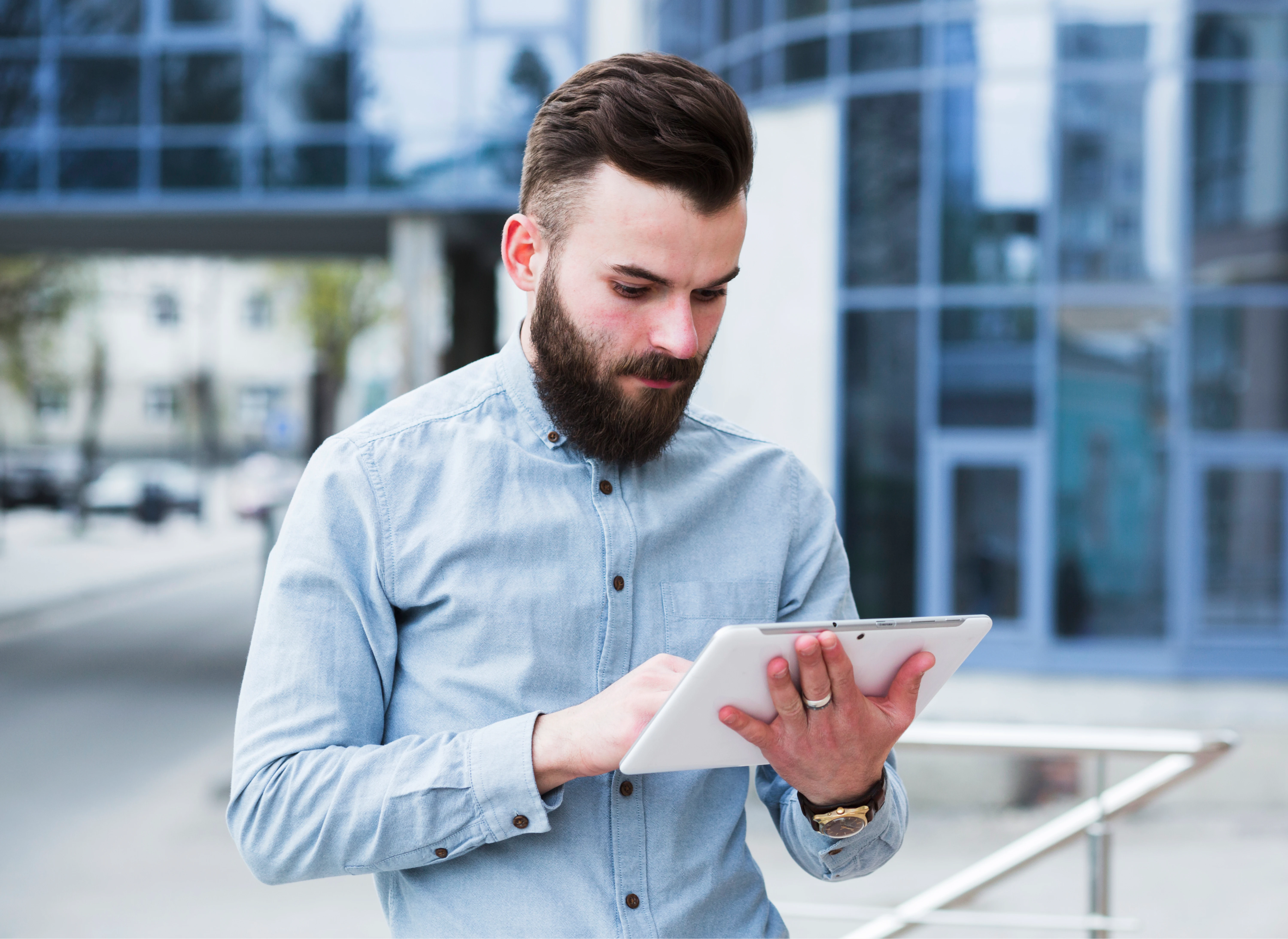 portrait_young_businessman_standing_outside_office_building_using_digital_tablet_1
